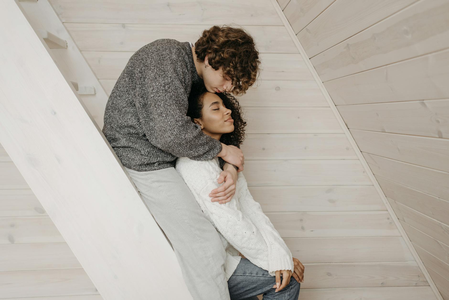 Przytulająca się w domu para różnych ras odbudowująca bliskość