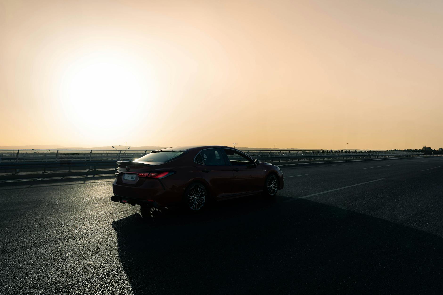 Czerwona Toyota jedzie pustą autostradą o zachodzie słońca