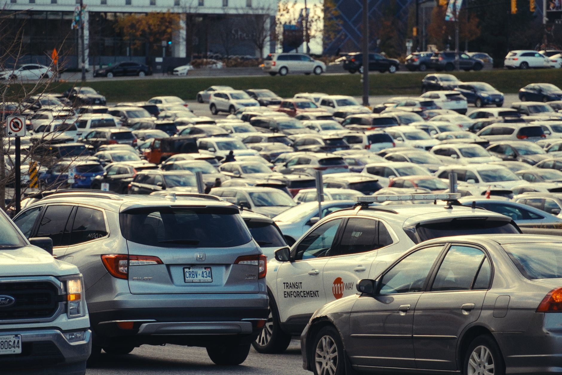 Duży miejski parking w dzień z wieloma zaparkowanymi samochodami