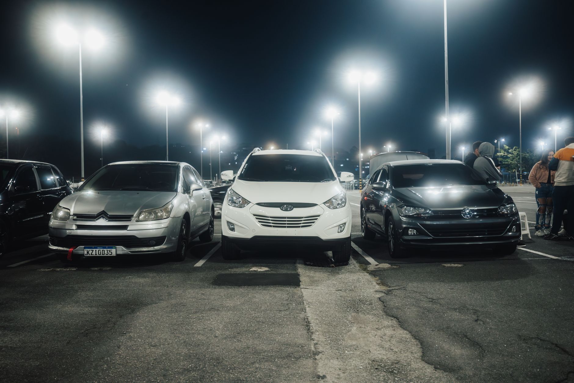 Samochody na nocnym, jasno oświetlonym parkingu ulicznym